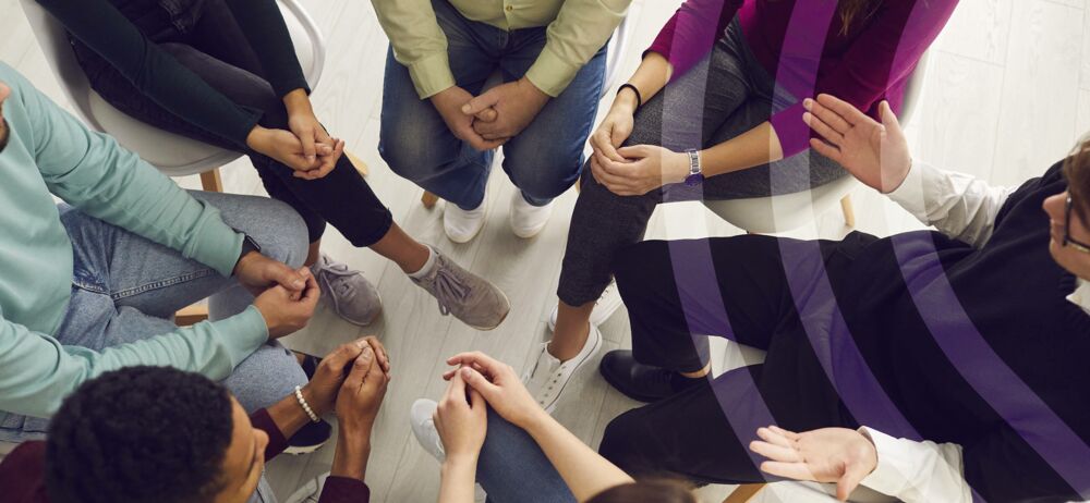 Eine Gruppe von Menschen sitzt in einem Stuhlkreis gegenüber