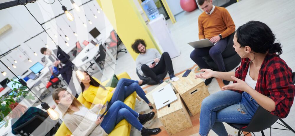 Eine Gruppe von Menschen sitz im modernen Büro und führt eine Unterhaltung