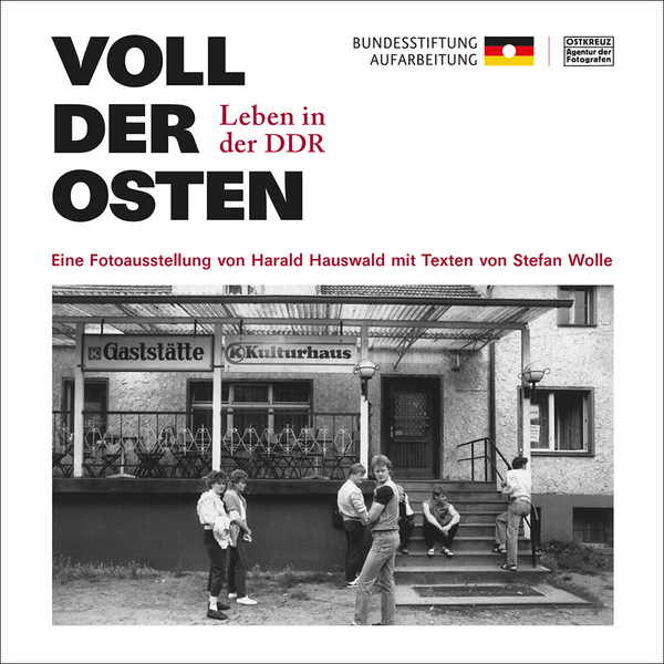 Plakat der Fotoausstellung von Harald Hauswald mit Texten von Stefan Wolle mit dem Titel „Voll der Osten. Leben in der DDR“. Zu sehen ist ein schwarzweiß Foto aus der DDR mit einer Gruppe von Jugendlichen vor einer Gaststätte. Mit dem Link öffnet sich ein